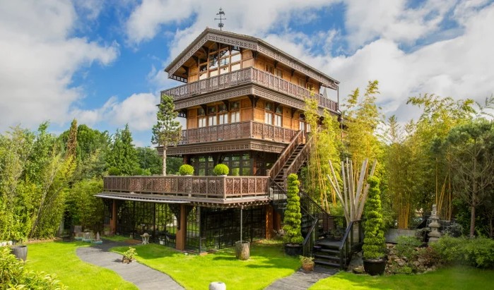 The Chalet on Hampton Court Road, a tall carved wooden chalet with balconies, set in a garden of bamboo and lawn